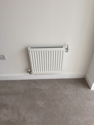 New white radiator installed neatly against a finished wall